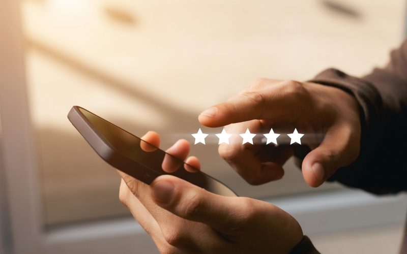 A male customer gives a five-star rating on their smartphone, satisfaction, customer service experience. Service Rating Reviews and Satisfaction Survey Concept.